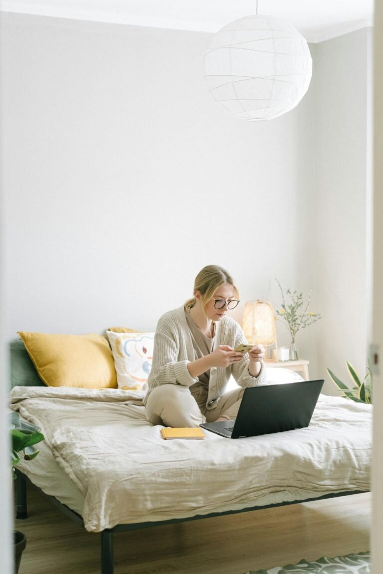 Photo of Woman Sitting on Bed While Using Smartphone